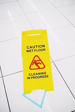 A two-sided caution wet floor sign placed on tile flooring by Floodco USA technician ahead of cleaning job.