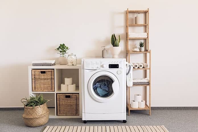 A medium size washer and dryer surrounded by wooden shelves on commercial flooring
