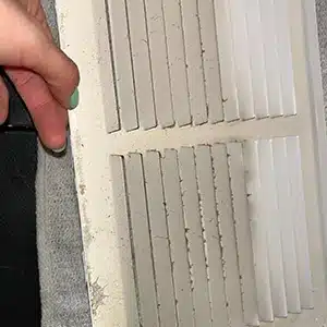 A dirty vent cover with noticeable dust build-up prior to the start of a professional cleaning service.