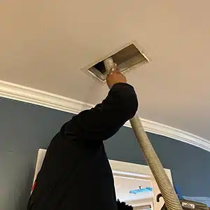 A technician is cleaning out an air duct with specialized equipment, demonstrating professional duct cleaning in action.