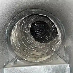 Interior view of a dirty air duct before professional cleaning, showing accumulated dust and debris.